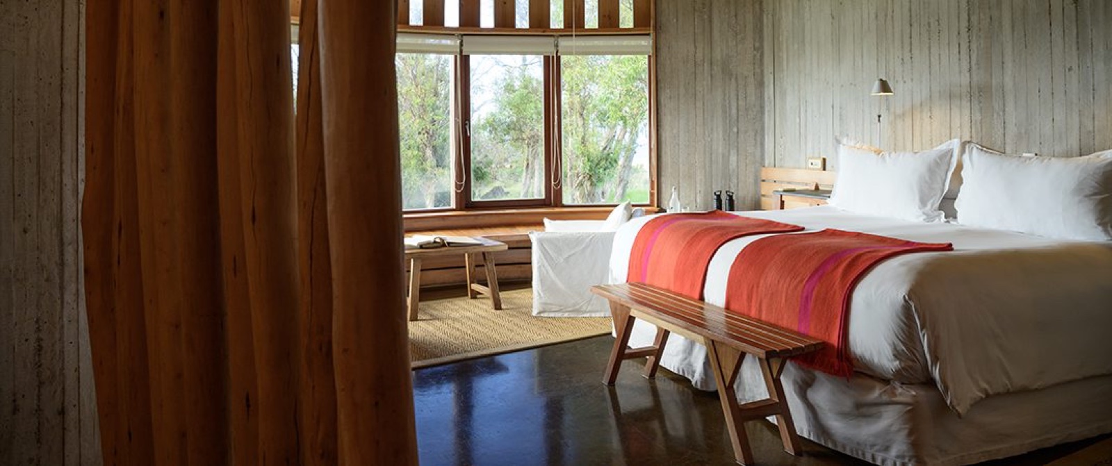 Habitación de lujo con madera natural, manta tejida y ventanal al paisaje de Rapa Nui